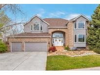 Beautiful two-story home with brick and stucco, arched entryway, three-car garage, and professionally landscaped front yard at 10773 Cougar Rdg, Lone Tree, CO 80124