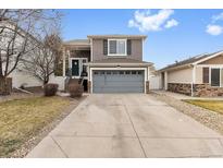 Two-story home with gray siding, an attached garage, and a concrete driveway at 4599 Argonne St, Denver, CO 80249