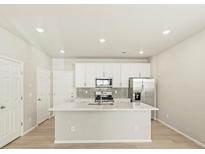 Bright kitchen features white cabinets, stainless steel appliances, and a quartz island at 20982 E 66Th Ave, Aurora, CO 80019