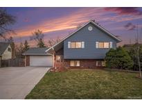 Charming two-story home with blue siding, brick accents, well-kept lawn, and attached two-car garage at 7746 W Quarto Dr, Littleton, CO 80128