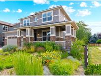 Charming two-story home featuring a welcoming front porch and beautifully landscaped front yard with vibrant flowers at 1902 Pioneer Cir, Lafayette, CO 80026