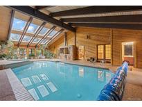 Bright indoor pool with brick BBQ, skylights, wood walls, and a vaulted beamed ceiling at 7351 Poppy Way, Arvada, CO 80007