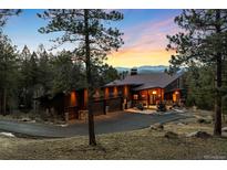 Stunning modern home featuring a three-car garage and a lush, wooded landscape with mountain views at 5976 Stone Creek Dr, Evergreen, CO 80439