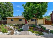 Charming brick home featuring a beautifully landscaped front yard and brick walkway to a red front door at 6020 Quail St, Arvada, CO 80004