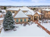 Luxury home with snow covered landscaping, mountain views, and stone accents at 774 Chamberlain Way, Highlands Ranch, CO 80126