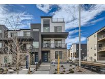 Modern two-story townhome with dark and light exterior finishes, balcony, and walkway at 1714 Peak Loop, Broomfield, CO 80023