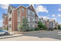 Apartment building exterior boasts brick and gray siding, complemented by lush landscaping and a well-maintained facade at 14221 E 1St Dr # 208, Aurora, CO 80011