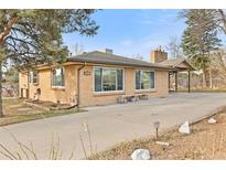 Charming single-story brick home featuring a spacious driveway and mature landscaping at 8800 W 73Rd Pl, Arvada, CO 80005