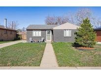 Charming single-story home with grey brick, lush lawn, and inviting front porch seating area at 373 S Locust St, Denver, CO 80224
