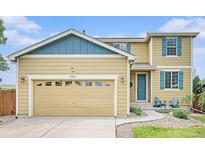 Charming home featuring a two-car garage, well-kept lawn, and a welcoming entrance with blue accents at 828 Lehigh Cir, Erie, CO 80516