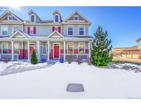 Two-story townhome with red door, snow-covered lawn, and red brick accents at 14653 E Crestridge Dr, Centennial, CO 80015