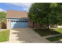 Charming single-Gathering home with a well-manicured lawn, brick facade, and a blue garage door at 13959 E 106Th Ave, Commerce City, CO 80022
