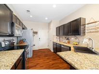 Well-lit kitchen features dark cabinets, stainless steel appliances, and beautiful granite countertops at 12744 Leyden St # F, Thornton, CO 80602