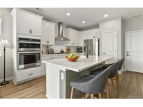 Bright kitchen featuring white cabinets, stainless steel appliances, and a center island with barstool seating at 7875 Yampa River Ave, Littleton, CO 80125