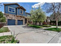 Charming two-story home with a stone facade, blue siding, a two-car garage, and a well-manicured front yard at 25245 E Park Crescent Dr, Aurora, CO 80016