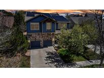 Beautiful two-story home featuring a stone and blue-paneled facade, two-car garage, solar panels and landscaped front yard at 25245 E Park Crescent Dr, Aurora, CO 80016