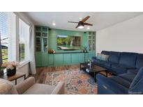 Cozy living room features built-in shelving, large windows, ceiling fan, and comfortable seating at 12826 Lake Port St, Longmont, CO 80504