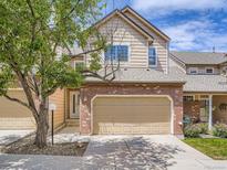 Charming home featuring a brick facade, beige siding, well-maintained lawn, and a two-car garage at 6827 S Webster St # E, Littleton, CO 80128