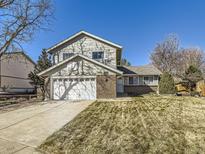 Two story home featuring an attached two-car garage, basketball hoop, and a low maintenance lawn at 13853 W 66Th Pl, Arvada, CO 80004