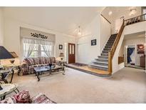 Inviting living room featuring a soaring ceiling, plush carpet, and a staircase leading to the upper level at 9001 W Chatfield Dr, Littleton, CO 80128
