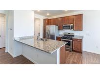 This modern kitchen features stainless steel appliances, stylish wood cabinets, and granite countertops at 4605 Copeland Loop # 103, Highlands Ranch, CO 80126