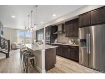 Modern kitchen featuring stainless steel appliances, pendant lighting, and a spacious island with bar seating at 9072 E 47Th Ave, Denver, CO 80238