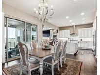 Elegant dining room featuring a chandelier, stylish furniture, and seamless access to the outdoors at 8651 S De Gaulle Ct, Aurora, CO 80016