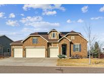 Charming two-story stone home with a three-car garage and well-manicured lawn at 8651 S De Gaulle Ct, Aurora, CO 80016