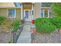 Charming front entrance with gray stone steps, red flower pots, and freshly planted green foliage at 18578 E Whitaker Cir # A, Aurora, CO 80015