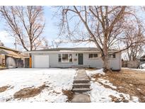 Charming single-story home with a gray brick facade, an attached garage, and a walkway leading to a green front door at 4110 W Floyd Ave, Denver, CO 80236