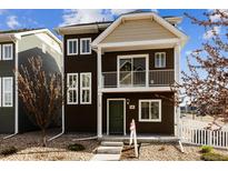 Two-story home featuring a balcony, brown siding, green door, manicured landscaping, and a well-maintained front yard at 5383 Andes St, Denver, CO 80249