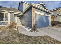 Two-story house with blue siding, stone accents, and a two-car garage at 10048 Deer Creek St, Highlands Ranch, CO 80129