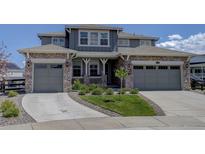 Charming two-story home with a stone and siding exterior, three-car garage, and well-manicured front yard at 22593 E Piccolo Way, Aurora, CO 80016