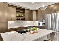 Close up of kitchen island with stainless steel appliances, modern cabinets, and white counter tops at 6619 E Lowry Blvd # 112, Denver, CO 80230