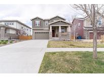 Inviting two-story home featuring a spacious driveway, covered porch, and neutral paint scheme with stone accents at 5937 N Orleans St, Aurora, CO 80019