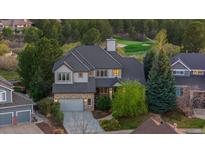 Stunning two-story home with stone accents, a well-manicured lawn, and a golf course view at 7071 Turweston Ln, Castle Pines, CO 80108
