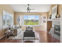 Bright living room featuring hardwood floors, a fireplace, and a large window with neighborhood views at 22455 E Plymouth Cir, Aurora, CO 80016