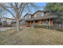 Charming two-story home featuring a manicured lawn, brick accents, and an inviting covered porch at 7590 S Reed Ct, Littleton, CO 80128