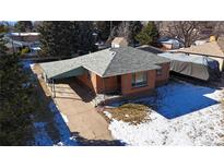 Brick ranch home with attached carport, driveway, and snowy yard at 4830 W Vassar Ave, Denver, CO 80219