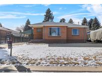 Brick ranch home with snowy lawn and carport at 4830 W Vassar Ave, Denver, CO 80219