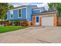 Charming two-story home boasts a blue exterior, white trim, stone accents, well maintained yard and large driveway at 1922 Danube Way, Aurora, CO 80011