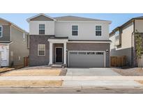 Charming two-story home with gray brick accents and a two-car garage at 6074 Hourglass Dr, Brighton, CO 80601