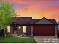 Charming brick home featuring a two-car garage, landscaped front yard, and warm sunset lighting at 11256 W 104Th Ave, Broomfield, CO 80021