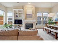Bright living room featuring a fireplace, built-in shelving, and large windows with natural light at 9580 E 5Th Ave, Denver, CO 80230
