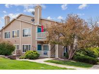 Tan two-story condo with private balcony and mature landscaping under a blue sky at 3847 Mossy Rock Dr # 104, Highlands Ranch, CO 80126