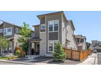 Contemporary gray home featuring stone accents, a small front yard, and modern architectural details at 6700 Clay St, Denver, CO 80221