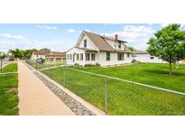 Charming two-story home with a well-maintained lawn and chain-link fence at 276 N 5Th Ave, Brighton, CO 80601