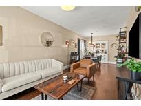 Inviting living room with a sofa, armchair, wood floors and a dining area in the background at 1847 W 41St Ave, Denver, CO 80211