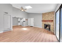 Inviting living room with vaulted ceilings, skylight, wood floors, stone fireplace, and sliding door to the outside at 12023 E Harvard Ave # 203, Aurora, CO 80014