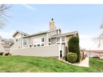 An exterior view of the home showing a two-story home with gray siding and a stone chimney at 6858 Zenobia St # 9, Westminster, CO 80030